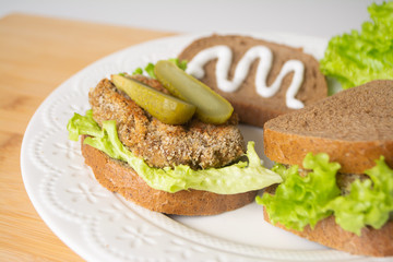 Veggie bean burger sandwiches with mayo, lettuce, tomatoes and pickled cucumber