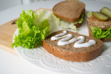 Veggie bean burger sandwiches with mayo, lettuce, tomatoes and pickled cucumber