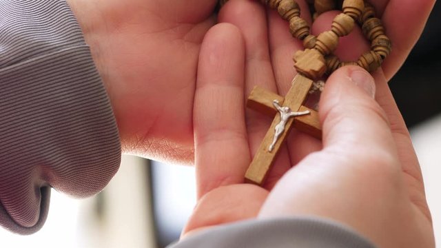 Female hands gently holding and caressing  a Christian Pendant necklace with a Jesus Christ crucified on a Cross.