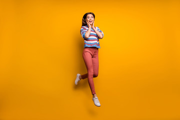 Full size photo of astonished girl look good incredible discount impressed jump feel rejoice scream touch hands face wear sweater footwear isolated over bright color background