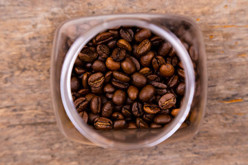 coffee beans in a glass jar on a wooden background, top view