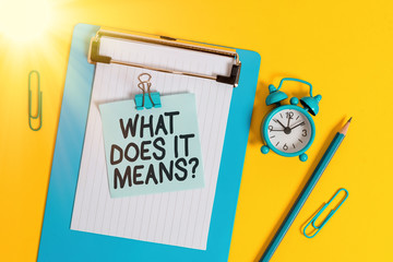 Conceptual hand writing showing What Does It Means Question. Concept meaning asking meaning something said and do not understand Clipboard sheet note pencil clips alarm clock colored background