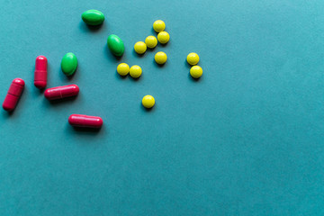 Tablets and caplets on cyan blue background, yellow, green and orange pills on top left corner of the photo, vitamins to fight virus and improve immunal system, text space, copy space