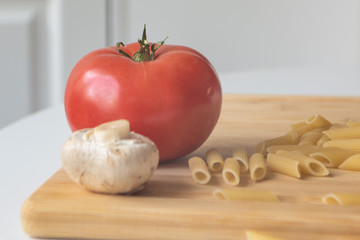 Ingredients for tradional italian pasta dish: dry penne, tomatoes, basil, mushrooms and garlic