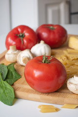 Ingredients for tradional italian pasta dish: dry penne, tomatoes, basil, mushrooms and garlic