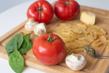 Ingredients for tradional italian pasta dish: dry penne, tomatoes, basil, mushrooms and garlic