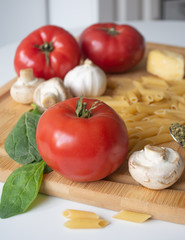 Ingredients for tradional italian pasta dish: dry penne, tomatoes, basil, mushrooms and garlic