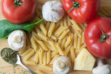 Ingredients for tradional italian pasta dish: dry penne, tomatoes, basil, mushrooms and garlic