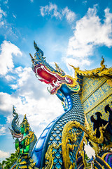 Fototapeta na wymiar Statue of dragon at Wat Rong Suea Ten temple (blue temple) near Chiang Rai city, Thailand. Mystical sculpture of ancient beast. View from bottom with blue sky dynamic background