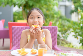 Cute asian girl enjoy to eat fresh orange on morning,