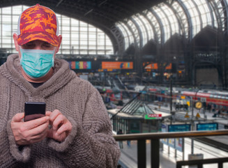 Model mit Gesichtsmaske zum Schutz vor einem Virus in einer Bahnhofshalle