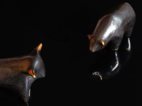A close up of the stock market symbols, bear and bull on a black background. Focus on a bull.