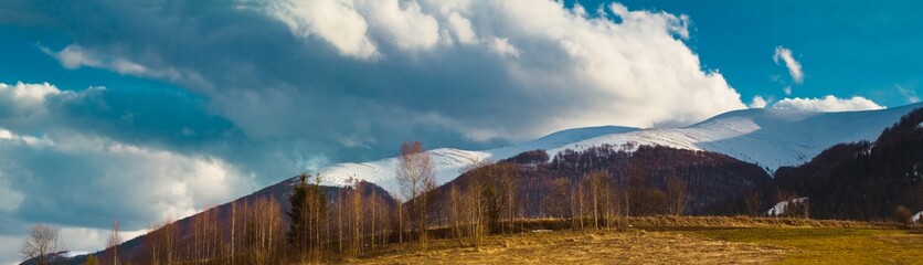 Carpathian Mountains in Transcarpathia, evening sun and low clouds on peak of Gemba mountain, covered with snow, early spring, world beauty explore concept, nature protection and ecology