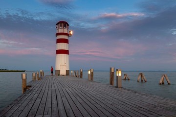Neusiedl am See - Lake Neusiedl, wooden pier lined with lights and leading to a white-red lighthouse at sunrise