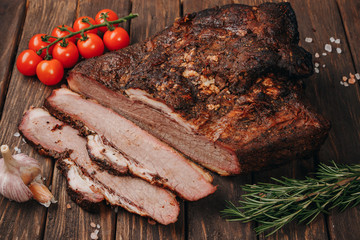 A piece of juicy smoked meat with spices on a wood background