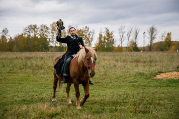 The concept of falconry. A man with a leather glove and a beautiful Falcon on handon a chestnut, red, and red horse