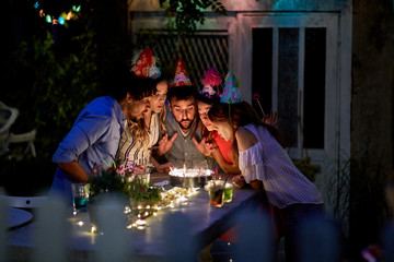 Friends with birtday girl blowing candles on cake