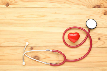 Stethoscope with red heart on brown wooden table