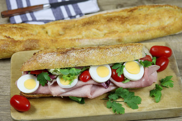 sandwich au jambon et crudités sur une planche à découper