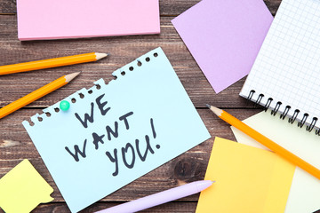 Text We Want You on paper with pencils on wooden table