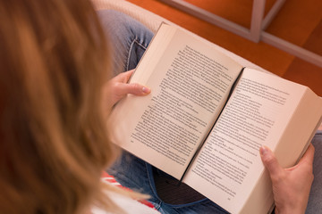 detalle de una chica leyendo en el sofá, colores cálidos y vista cenital