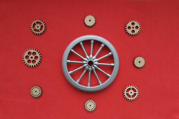 The wheel is grey, with wooden gears on a red background. The concept of the mechanism of movement.