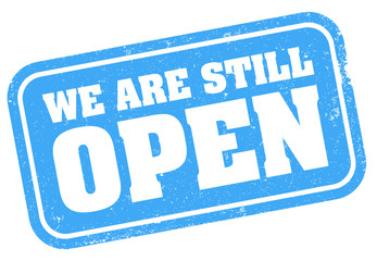grungy blue WE ARE STILL OPEN stamp or sign vector illustration