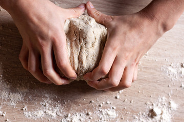 Working hands kneading bread dough. Wooden background