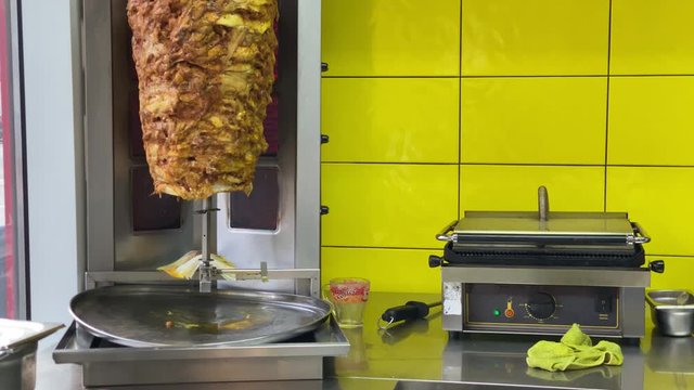 Skewered roasted chicken shawarma meat cooking and turning on rotating spit in fast food restaurant.