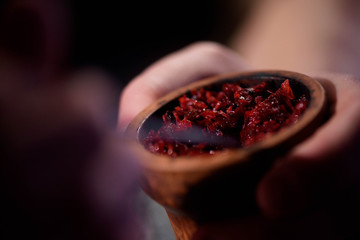 Barman fills black burnt ceramic bowl for hookah smoking different types of tobacco.