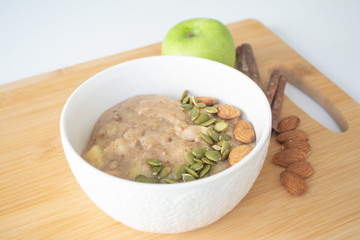 Healthy breakfast option: porridge oatmeal with cinnamon, apple and banana with almonds and pumpkin seeds sprinkled on top