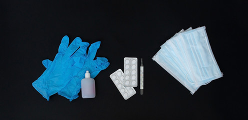 protective masks and gloves, tablets and a thermometer on a black background