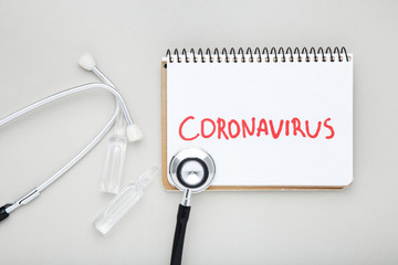 Text Coronavirus with medical ampoules and stethoscope on grey background