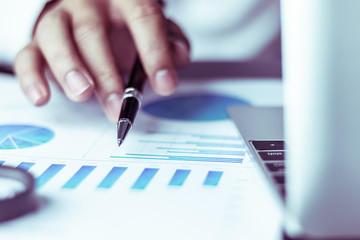 Business people use pen to point graphs to analyze company data and statistics from the chart.