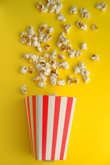  top view of popcorn spilling on yellow background 