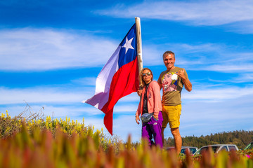The couple with Chilean flag on a background of blue cloudy sky