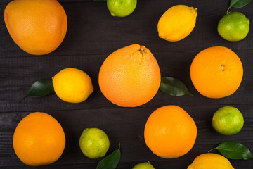 oranges, grapefruit, lemons and lime are scattered on the brown table.