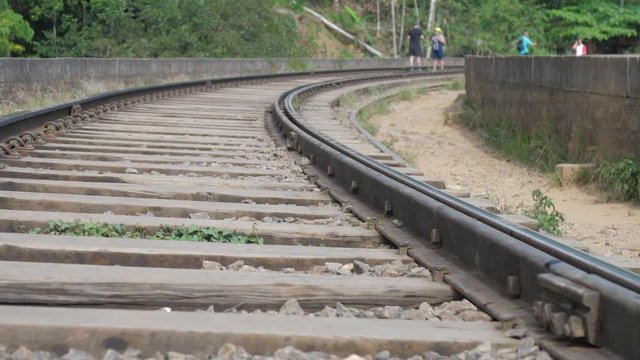 metal track on brown wooden sleepers with green grass waved by light wind near path slow motion closeup. Concept travel