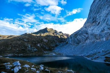Panoramic shot of a soft reflection of an Alpine mountain in Wolayer Lake, Austria. Completely still surface of the lake. Mountain is surrounded by morning haze. Peace of mind, calmness.