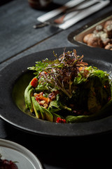 Ensalada de selección de lechugas y aguacate sobre fondo negro