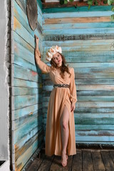 spring girl in a beige dress in a wreath of flowers against a blue wall