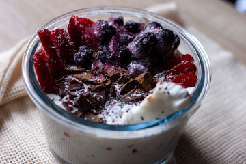 Healthy smoothie bowl with granola, fresh strawberries, blueberries, coconut, chocolate, yogurt and chia seeds. Healthy food, snack or breakfast.