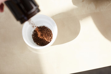 pouring coffee grounds into cupping bowl