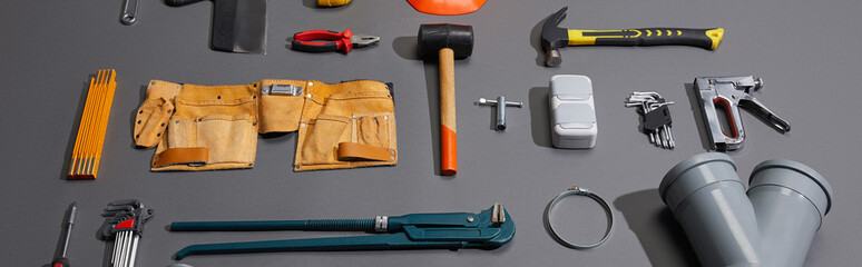 panoramic shot of industrial tools and tool belt on grey background