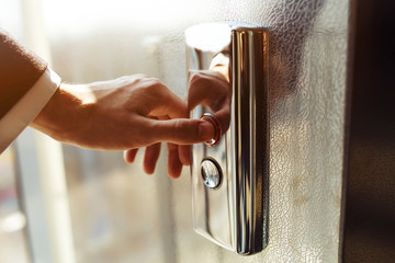 Finger presses the elevator button. Businessman pushing up elevator button. Human hand reaches for the button of the elevator call. © maxbelchenko