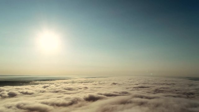 4k timelapse low angle view cloudscape with wind blowing white fluffy clouds passing the sun in clear sky with sunlight through the cloud.
