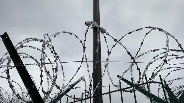 Welded wire mesh fence rigid security barrier with razor barbed wire and CCTV cameras.