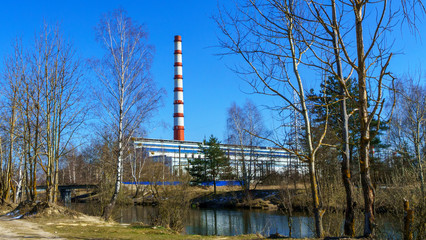 Chimney of thermal power station and water channel on classic blue sky background. Green power and ecological problem.