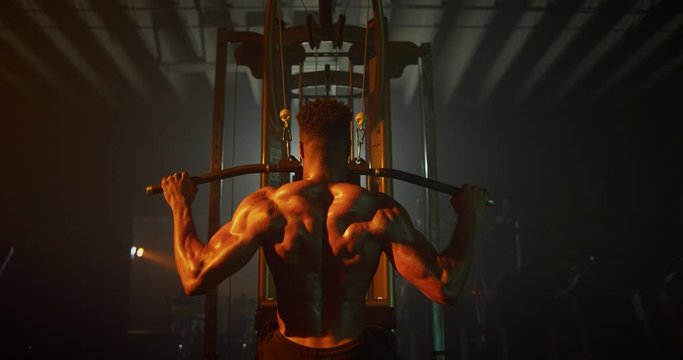 Man working out back muscles in dark gym
