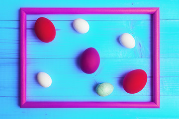 Easter eggs in picture frame on blue wooden background